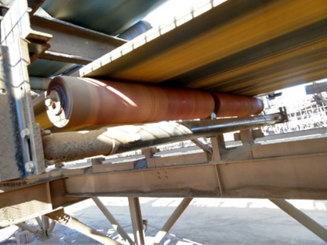 Close-up of a conveyor belt system in an industrial setting, showing rollers and supporting structure beneath the moving belt.